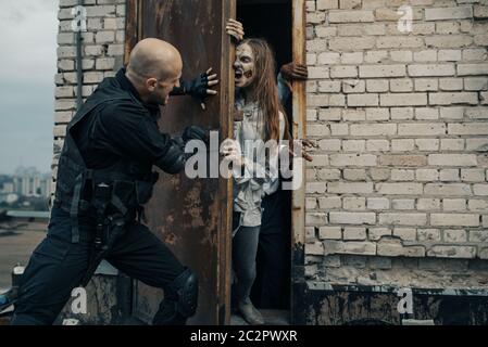 Military man do not let the zombies on the roof of a building, deadly chase. Horror in city, creepy crawlies attack, apocalypse Stock Photo