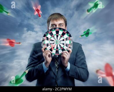 Businessman holding darts board infront face in his hands Stock Photo