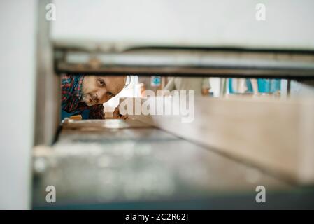 Carpenter works on plane machine, woodworking, lumber industry, carpentry. Wood processing on furniture factory Stock Photo