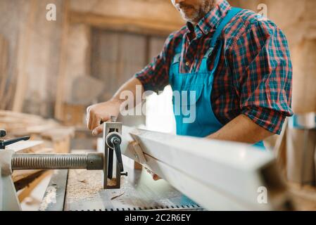 Carpenter works on plane machine, woodworking, lumber industry, carpentry. Wood processing on furniture factory Stock Photo