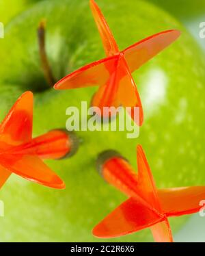 Three red arrows of darts in green apple. Close-up Stock Photo