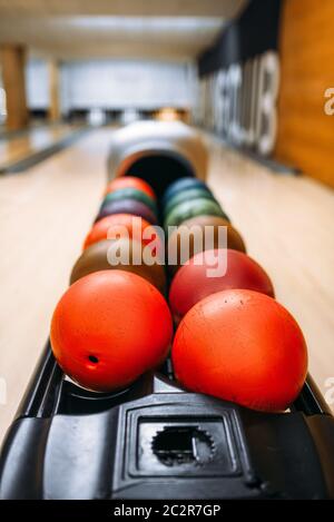 Color bowling balls in feeder, lane with pins on background, nobody. Bowling game concept Stock Photo