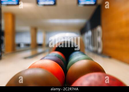 Color bowling balls in feeder, lane with pins on background, nobody. Bowling game concept Stock Photo