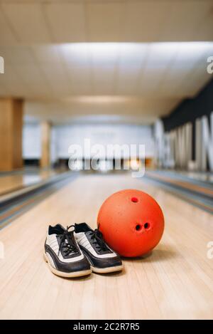 Bowling ball and house shoes on lane in club, pins on background, nobody. Bowl game concept, tenpin Stock Photo