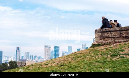 Jaffa, Israel - February 4, 2017: People relaxing and admiring the view of the Tel Aviv promenade with modern skyscrapers along the seacoast. Stock Photo