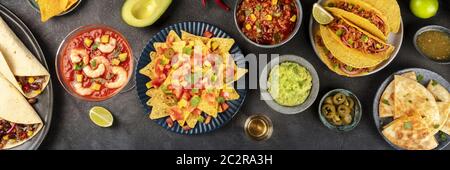 Mexican food overhead panoramic shot, many dishes of the cuisine of Mexico, flatlay on a dark background. Nachos, guacamole, shr Stock Photo
