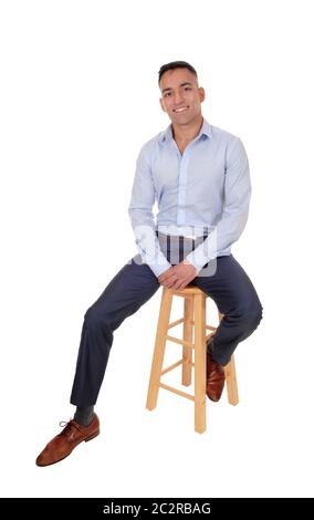 A happy east Indian man sitting relaxed on a chair taking a break,  smiling, in a blur dress shirt, isolated for white background Stock Photo