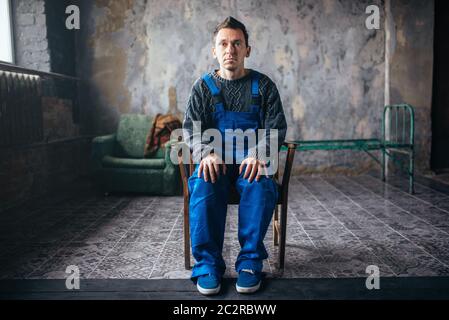 Crasy man in uniform sitting in the chair, psycho patient. Mentally ill people concept, stressed human Stock Photo