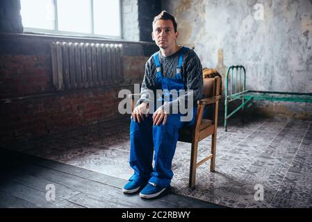 Crasy man in uniform sitting in the chair, psycho patient. Mentally ill people concept, stressed human Stock Photo