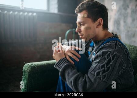 Madman in uniform with plasters on face and hands, psycho patient. Mentally ill people concept, crazy human Stock Photo