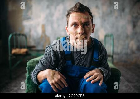 Madman in uniform mouth sealed with plaster, psycho patient. Mentally ill people concept, crazy human Stock Photo