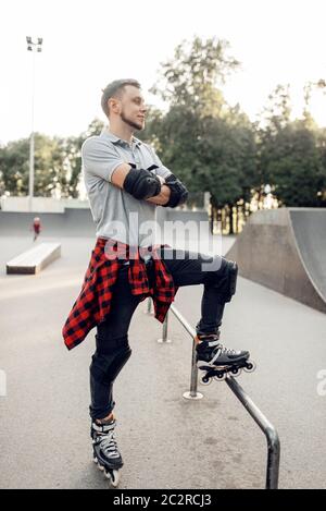 Roller skating, young male skater poses in skate park. Urban roller-skating, active extreme sport outdoors Stock Photo