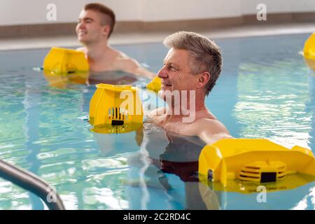 People in pool during water gymnastics physiotherapy doing exercises Stock Photo