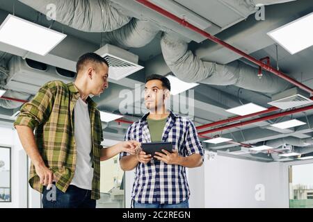 Horizontal low angle shot of two architects standing in unfinished building room discussing current project issues, copy space Stock Photo
