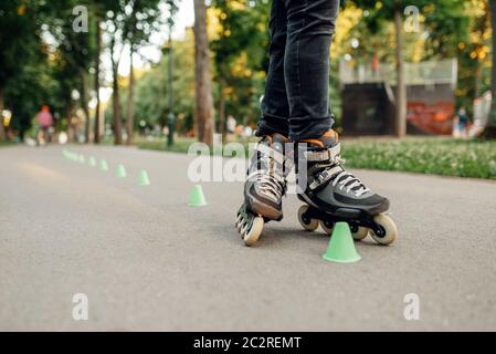 Roller skating, male skater rolling around the cones in park. Urban roller-skating, active extreme sport outdoors, youth leisure, rollerskating Stock Photo