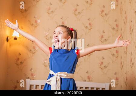Happy little girl hands up in bedroom. Stock Photo