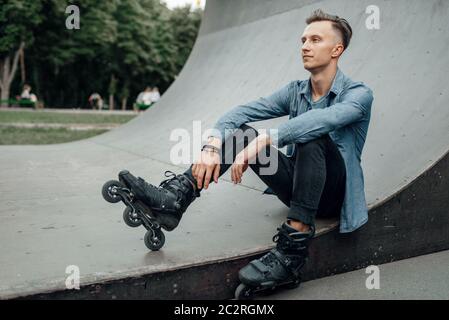 Roller skating, male skater poses on the ramp. Urban roller-skating, active extreme sport outdoors, youth leisure, rollerskating Stock Photo