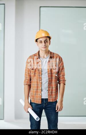 Portrait shot of modern construction worker wearing casual outfit and protective hardhat looking at camera Stock Photo