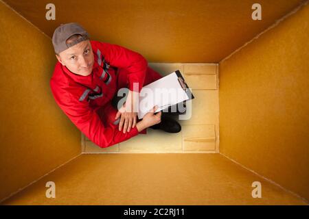 Sad mail courier sitting inside empty box Stock Photo