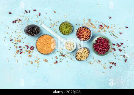 Legumes, shot from above on a blue background with a place for text. Vibrant pulses including colorful beans, lentils, chickpeas Stock Photo