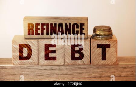 Reefinance Debt text on a wooden blocks and cubes and stack of coins. Overdur debts redeem and refinancing financial banking business concept Stock Photo