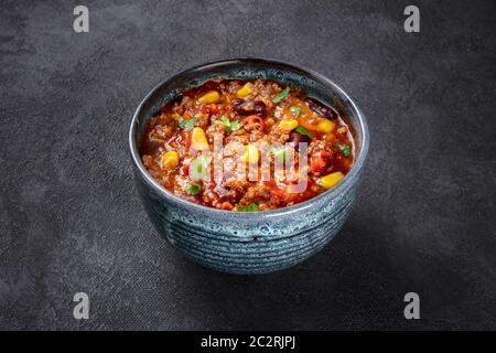 Chili con carne, a Mexican stew with beans, ground meat, corn, and chilli peppers, on a dark background Stock Photo