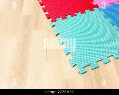 Soft rubber mat composed of colored blocks intersected with each other on a wooden floor Stock Photo