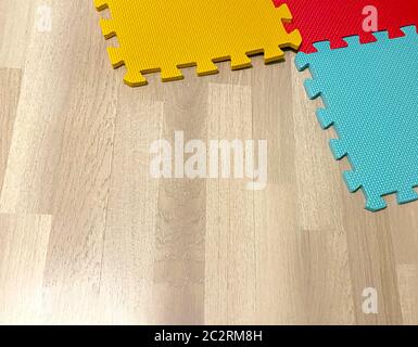Soft rubber mat composed of colored blocks intersected with each other on a wooden floor Stock Photo
