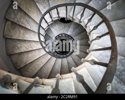 Ancient spiral staircase with decorated wrought iron handrails and marble steps inside an old palace Stock Photo