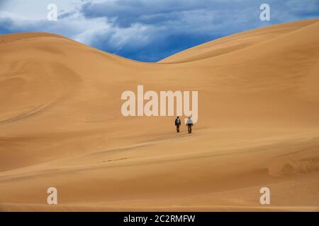 Travelers in desert dunes in mountains Stock Photo