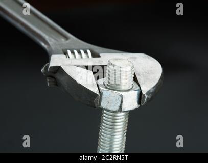 Macro shot of a bolt and a wrench isolated on black Stock Photo