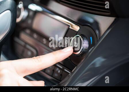 Air conditioner control panel, car cooling system. Finger presses the AC knob Stock Photo