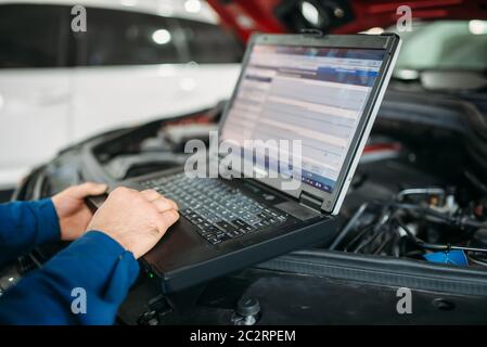 Engineer makes computer diagnostics of the car in autoservice. Vehicle wiring inspection Stock Photo