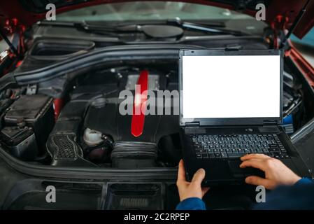 Engineer makes computer diagnostics of the car in auto-service. Vehicle wiring inspection Stock Photo
