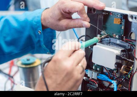 Electronics engineer man troubleshooting defects in a hardware product on his test bench Stock Photo