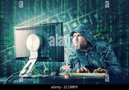 Hacker at desk looking at computer screen Stock Photo