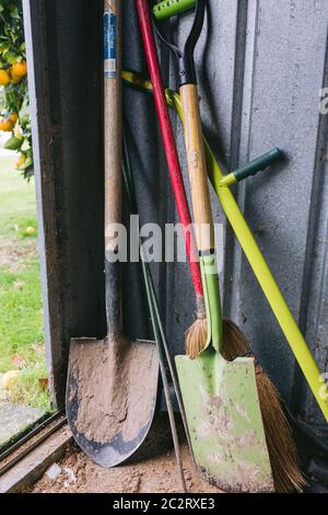 Garden Tools leaning in garden shed covered in dirt Stock Photo