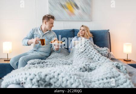 Love couple having romantic breakfast in bed with croissants and cookies. Man and woman eats dessert in bedroom, good morning. Happy lifestyle, beauti Stock Photo