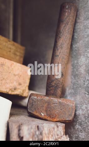 Old used Rusty Hammer leaning again steel sitting on a timber ledge Stock Photo