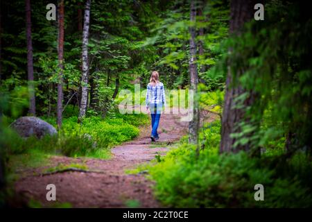 Woman on curved forest road in summer. Trees on sides of road Stock Photo