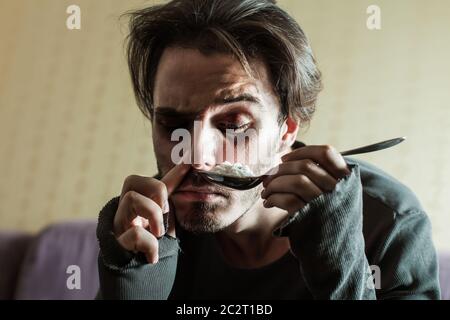 Addict in depression smells cocaine from a spoon. Abuse of drugs leads to a depression. Stock Photo