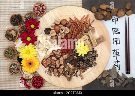 Chinese herbs with calligraphy script on rice paper with translation reading as traditional chinese herbs used in herbal medicine. Stock Photo