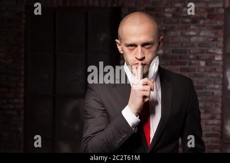 Silent killer explore oriental martial arts concept. Bald contract murderer in suit and red tie holds combat knife. Fighting knife is a dangerous weap Stock Photo