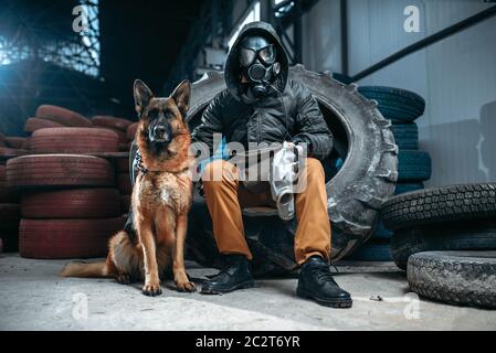 Stalker in gas mask and dog, friends in post apocalyptic world. Post-apocalypse lifestyle on ruins, doomsday, judgment day Stock Photo