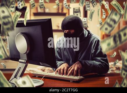 Hacker in mask stealing information and money at home Stock Photo