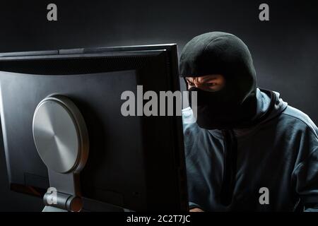 Hacker in mask is stealing information Stock Photo