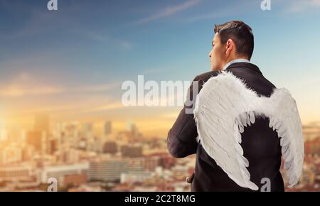 Businessman with angel wings on his back looking at the city Stock Photo