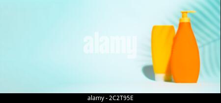 Two orange containers for lotion without label on blue background with leaf, space for text Stock Photo