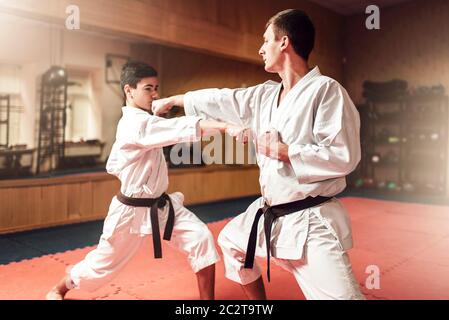 Martial arts karate masters in white kimono and black belts, self-defence practice in gym Stock Photo