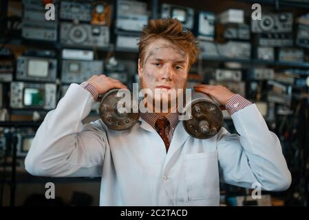 Strange scientist holds radiation devices in his hands, dangerous test in laboratory. Electrical testing tools on background. Lab equipment, engineeri Stock Photo